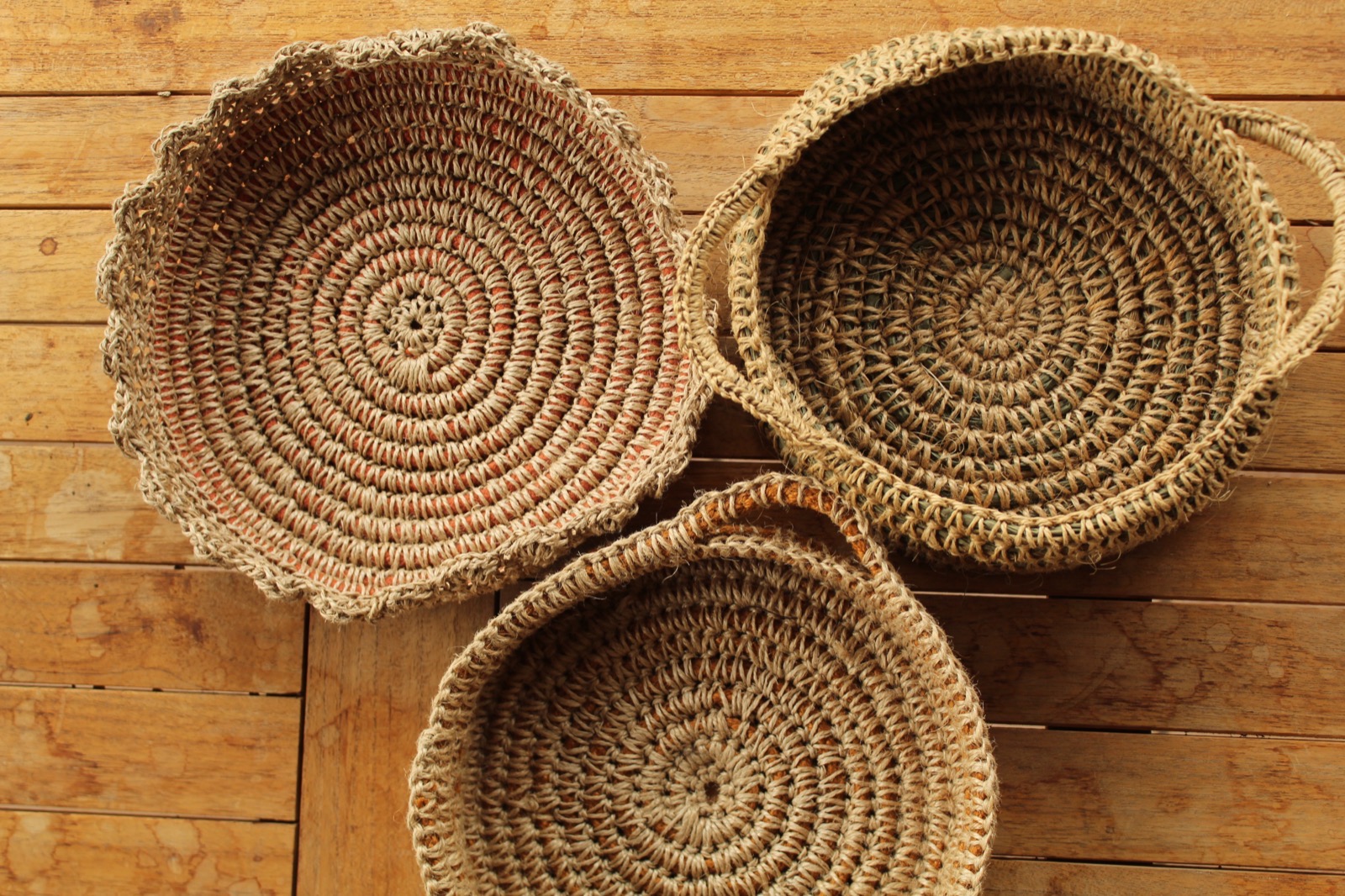 Piezas de fibra natural tejidas a mano, vistas desde arriba sobre madera
